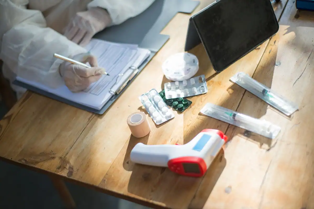 Medic completează un formular la birou, printre obiecte medicale și hârtii
