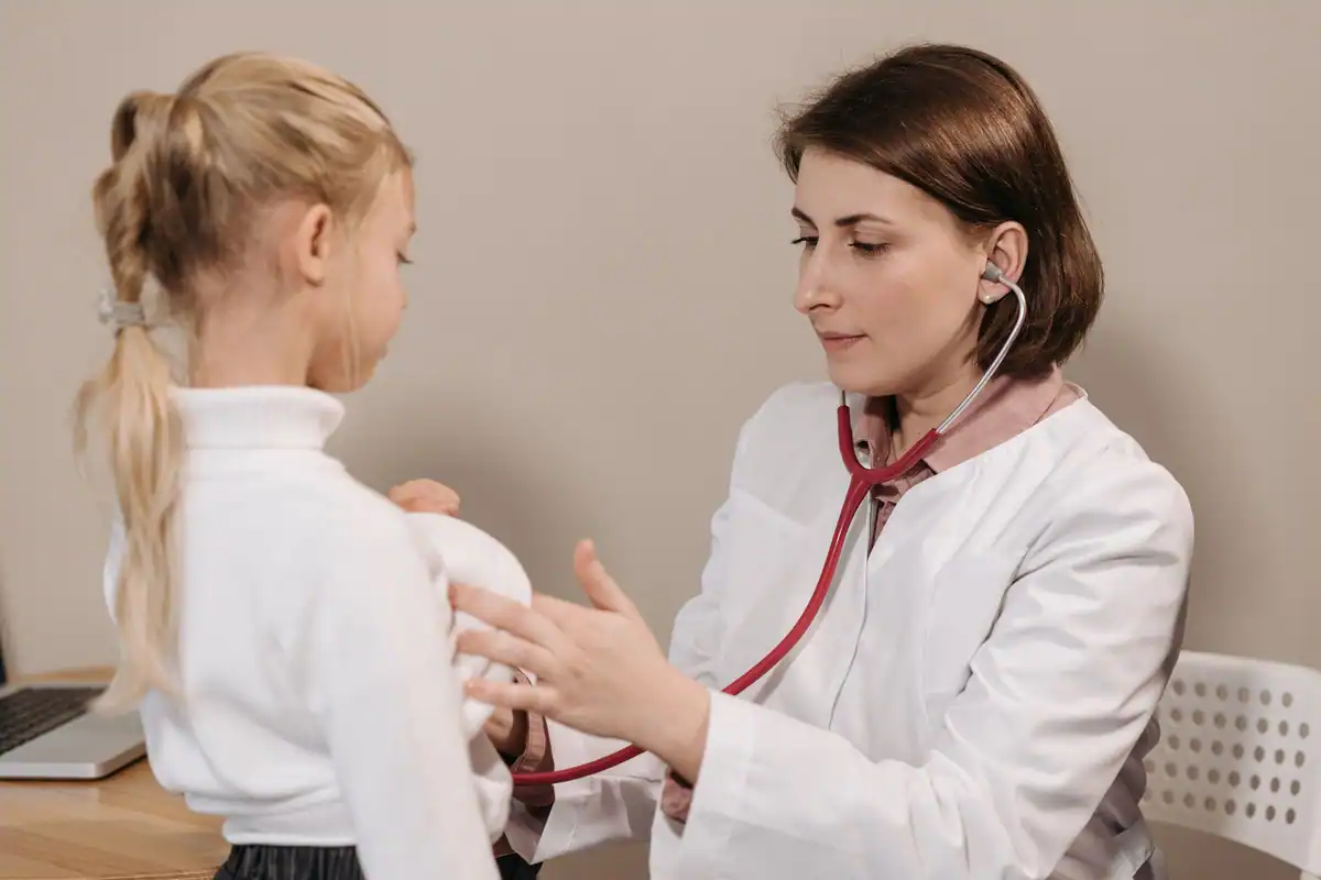 Medic ascultă cu stetoscopul pieptul unui copil în timpul unui control într-un cabinet de pediatrie