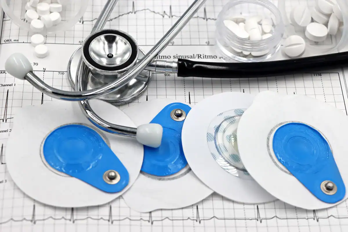 Stetoscop, electrozi pentru EKG și o foaie de trasee cardiace, pe un birou de cardiologie