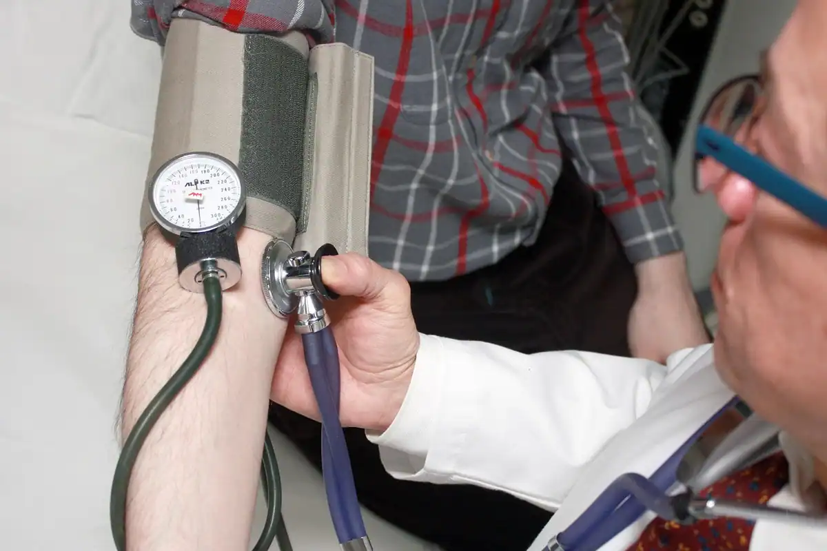 Medic măsoară tensiunea arterială a unui pacient cu un tensiometru manual și stetoscop