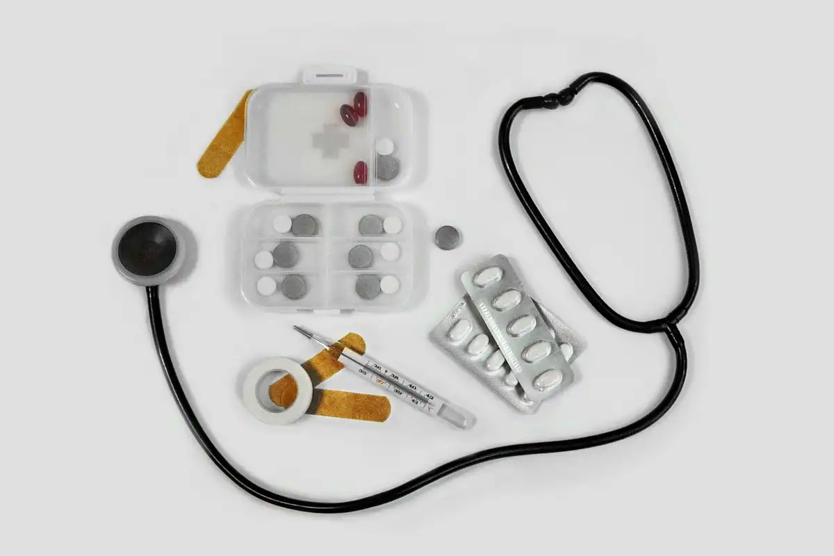 Medicamente, pastile și un termometru, așezate pe o suprafață albă