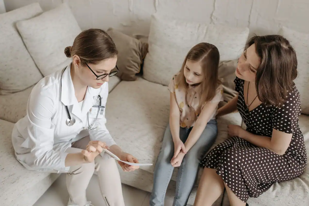 Medic explică diagnosticul unei fetițe și mamei sale, așezate împreună pe canapea