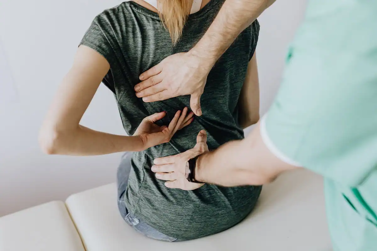 Medic examinează pielea de pe spatele unei paciente așezate pe canapeaua de consult