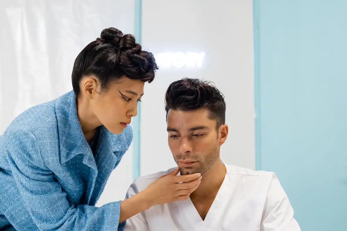 Medic examinează de aproape bărbia unui pacient, în timpul unui consult dermatologic