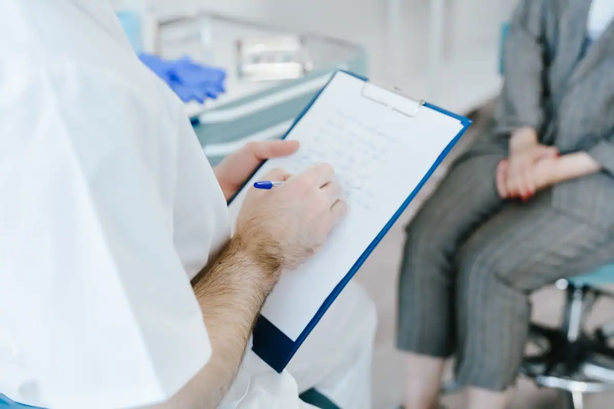 Medic notează pe un clipboard informațiile pacientului în timpul consultului
