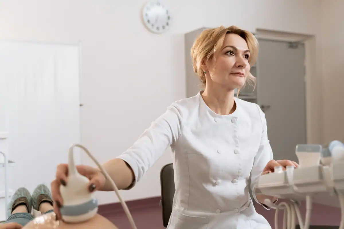 Medic efectuează o ecografie într-un cabinet ginecologic luminos, cu aparatul în mână