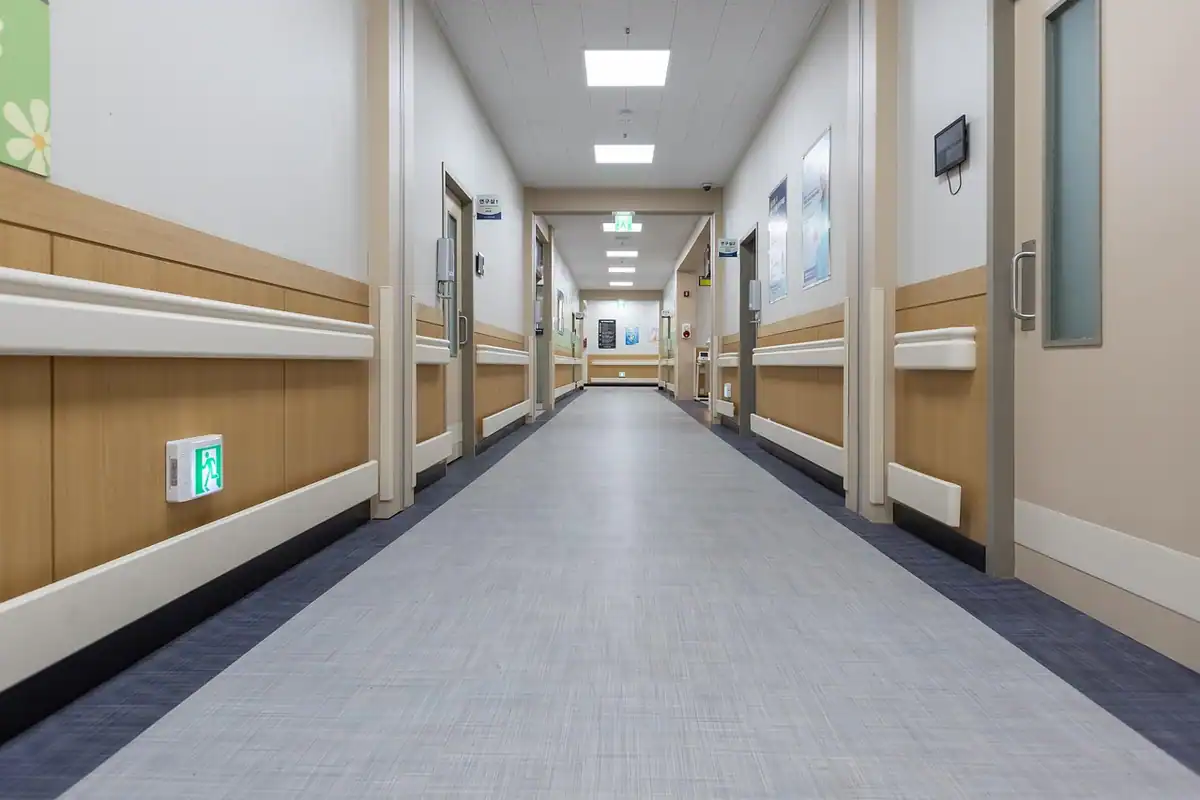 Coridor lung de spital, curat și luminos, cu uși către saloane și cabinete