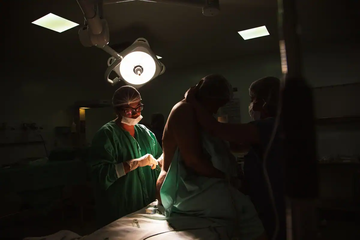 Echipă chirurgicală se pregătește de operație sub lămpile puternice ale sălii de operație