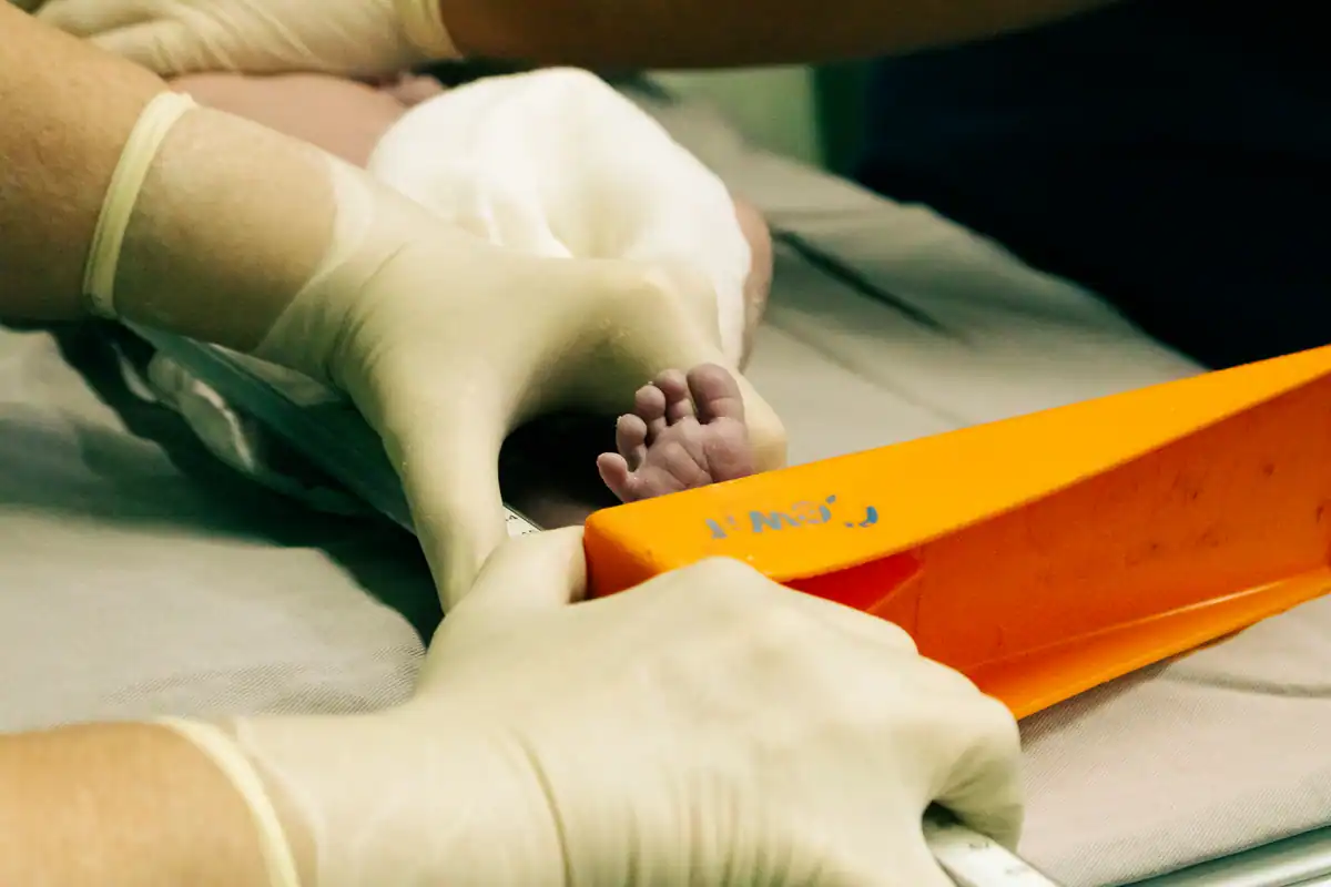Asistentă măsoară cu o riglă piciorul unui nou-născut, la un control medical